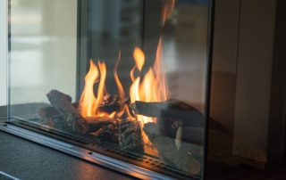 a fire burns in a glass fireplace, radiates heat